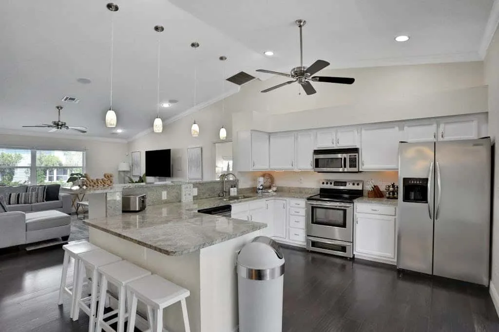 An open-plan kitchen and living area with a central island and stainless steel appliances.