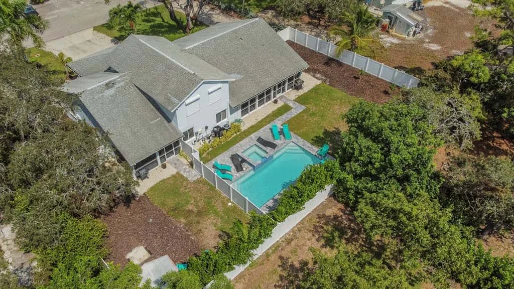 An aerial view shows a house beside a swimming pool and landscaped yard.