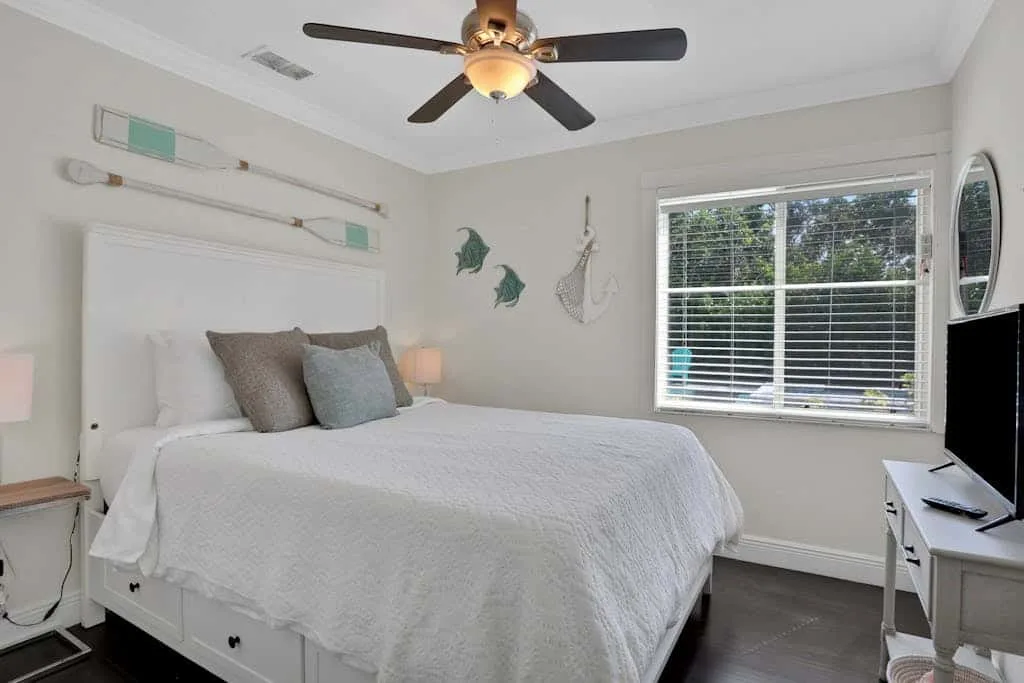 A bedroom with a bed, bedside tables, and a window with blinds.