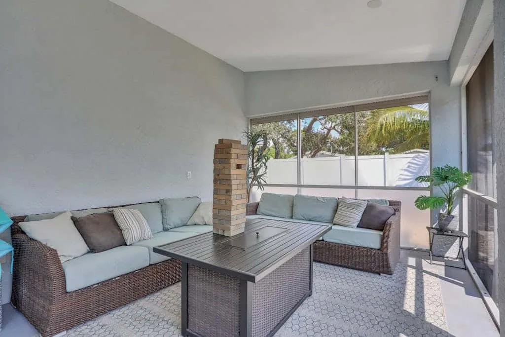 A bright enclosed patio has wicker seating around a low rectangular table.
