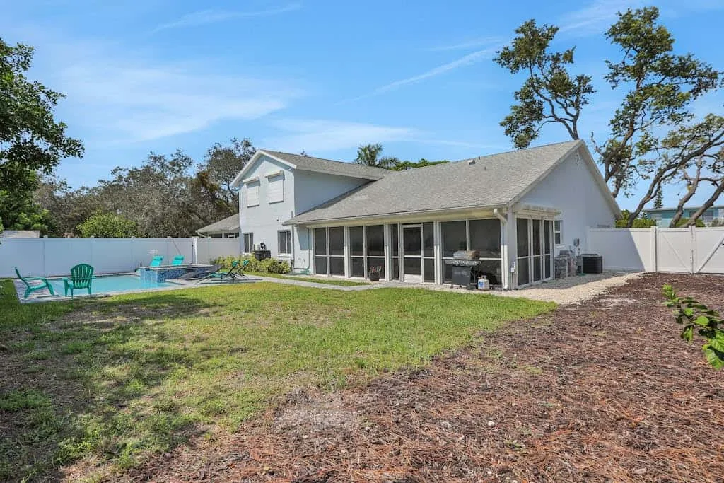 A house with a glass-enclosed patio and swimming pool in the yard.