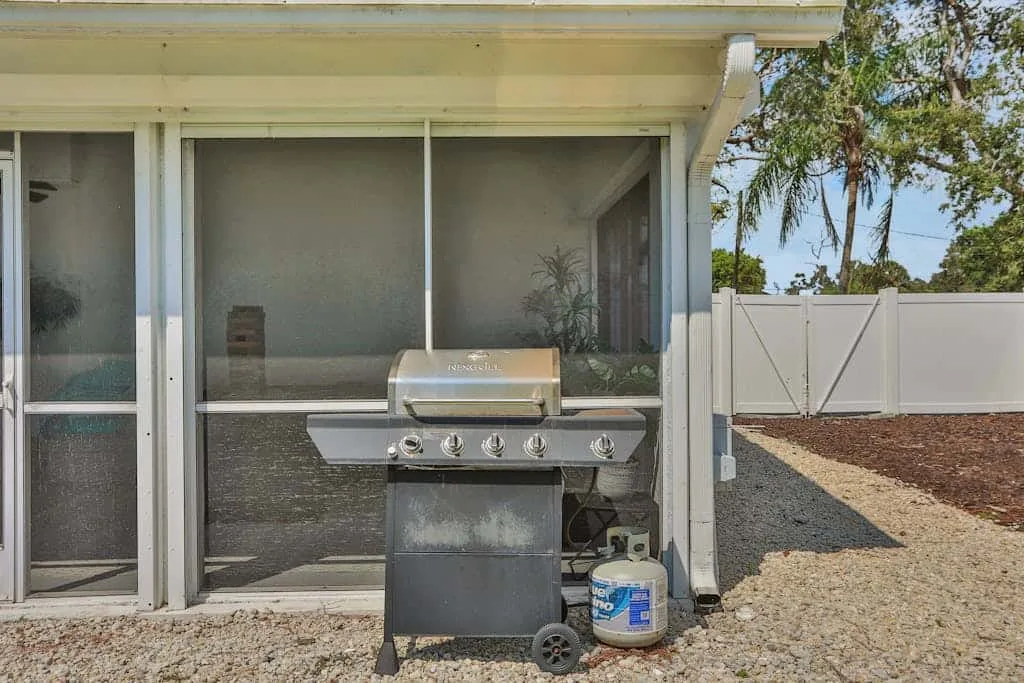 A covered outdoor grill stands in front of a screened porch.