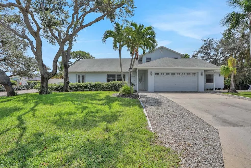 A single-story house with a garage sits beside a green lawn and driveway.
