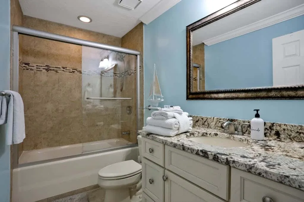A bathroom with a glass shower, bathtub, toilet, and vanity.