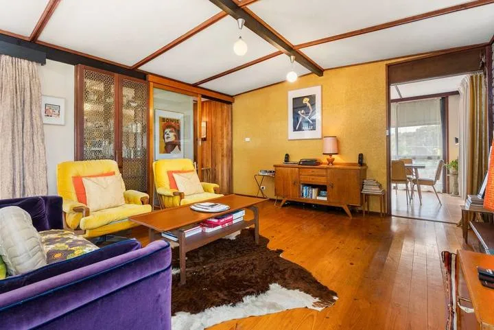 A living room with colorful seating, a coffee table, and a wooden sideboard.