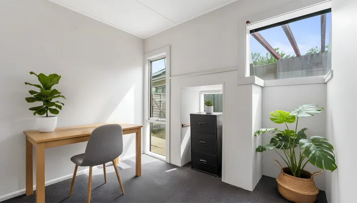 A bright room with a wooden desk, a chair, and potted plants.