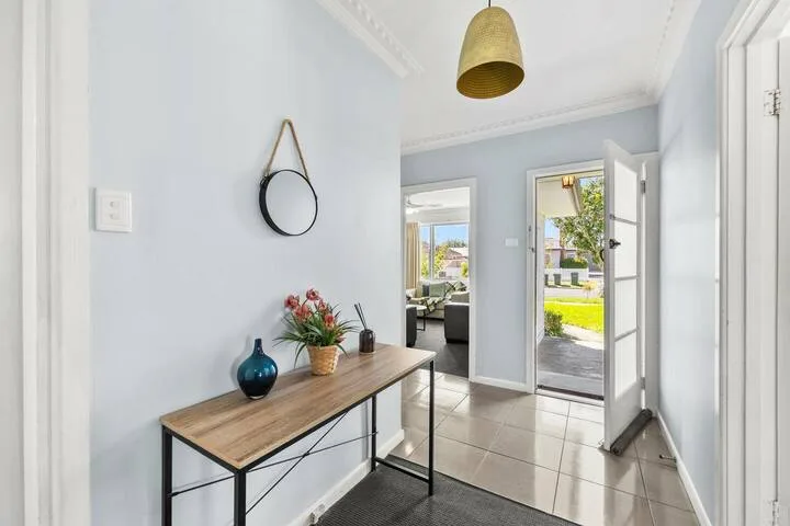 A bright entry hallway with a narrow console table and an open door.