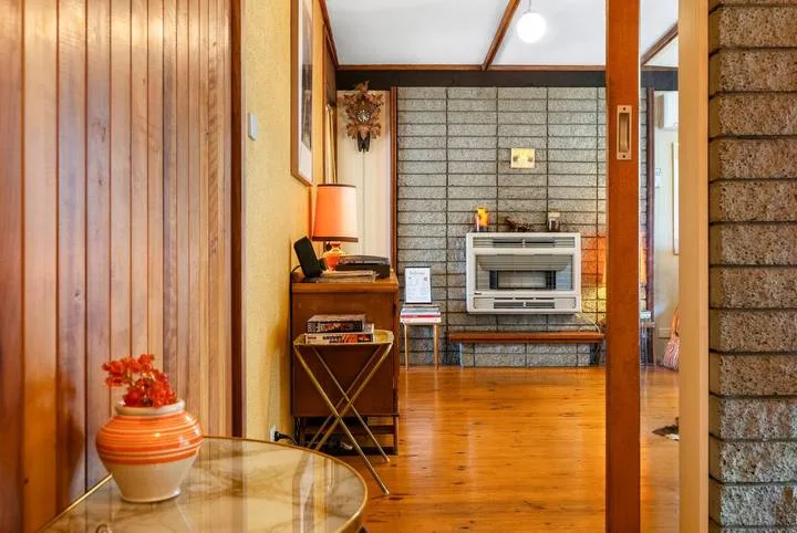 A wood-paneled sitting room with a low table and a wall-mounted television.