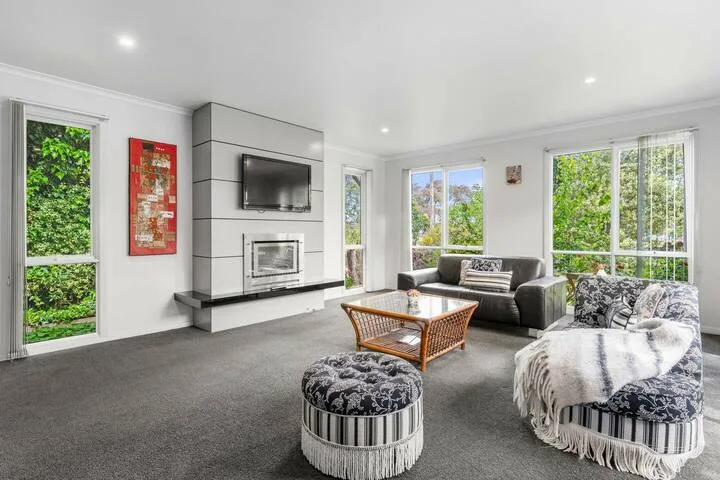 A bright living room with seating, a fireplace, and large windows.