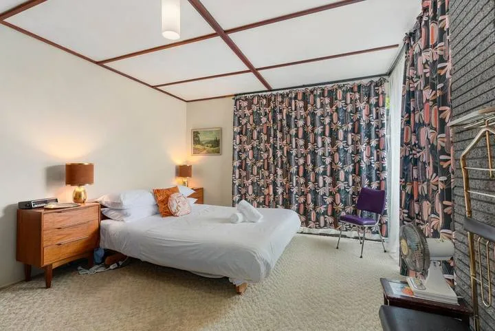 A bedroom with a bed, bedside tables, and patterned curtains.