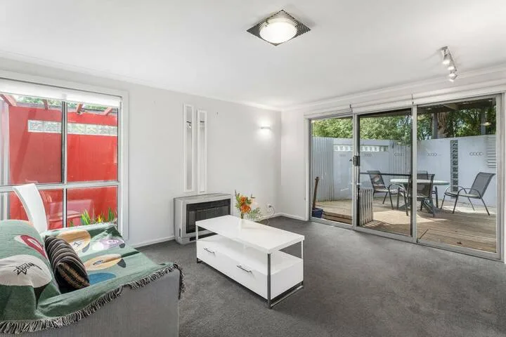 A bright living room with seating, a coffee table, and sliding doors opening onto a patio.