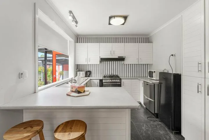 A bright kitchen with white cabinets, a central island, and dark appliances.