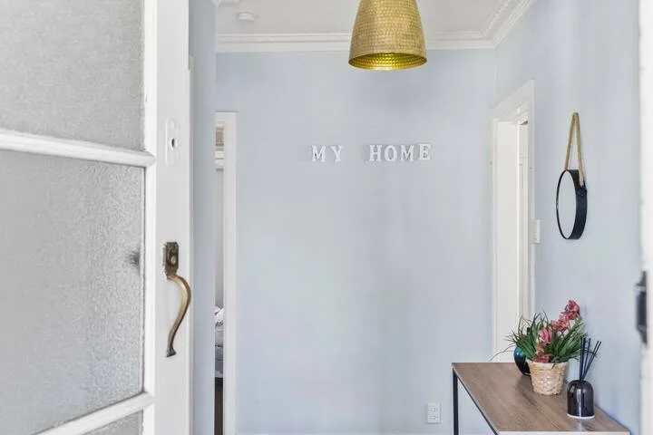 A pale blue entryway with a table and hanging pendant light.