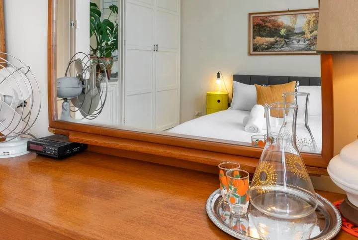 A bedroom with a neatly made bed and a framed landscape painting.