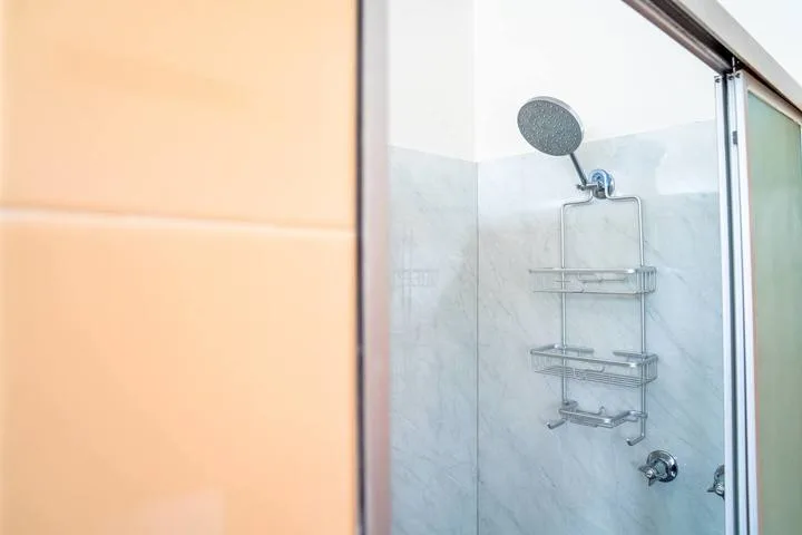 A shower with a wall-mounted showerhead and metal storage rack.
