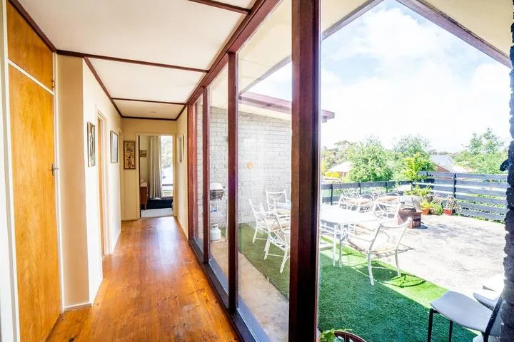A bright hallway with a wooden floor opens onto an outdoor patio.