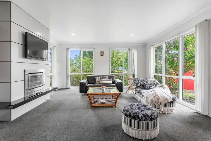 A bright living room with seating, a coffee table, and large windows.