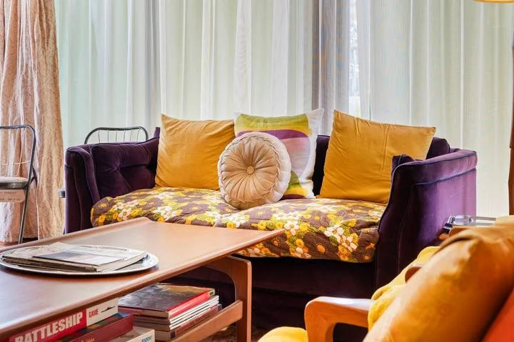 A colorful living room seating area with a purple sofa and coffee table.