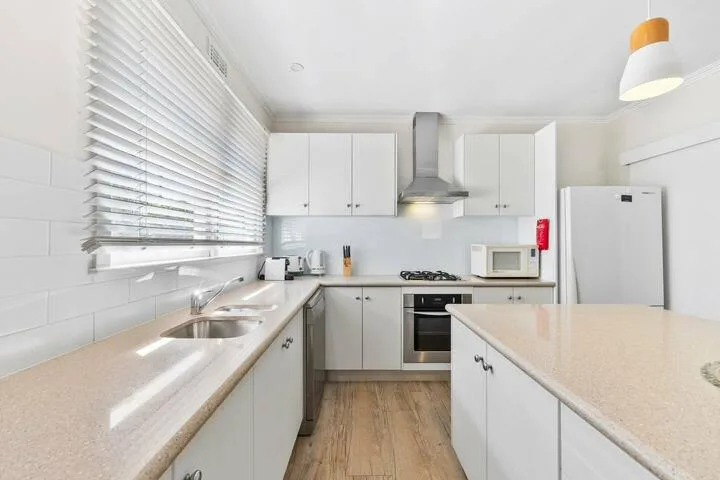 A bright kitchen with white cabinetry, a central island, and stainless steel appliances.
