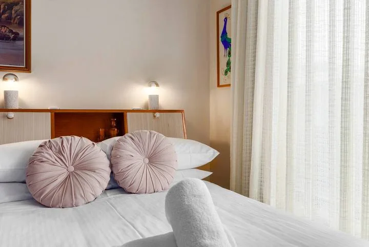 A bedroom with a neatly made bed and two round decorative pillows.