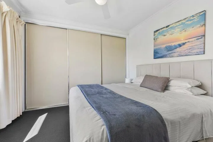 A bedroom with a bed and sliding closet doors.