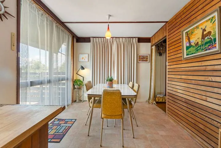 A dining area with a table and chairs beside large windows.