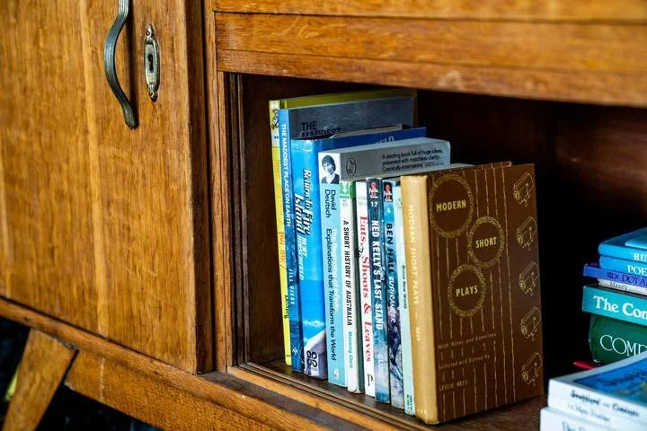 A wooden bookcase holds a row of books.