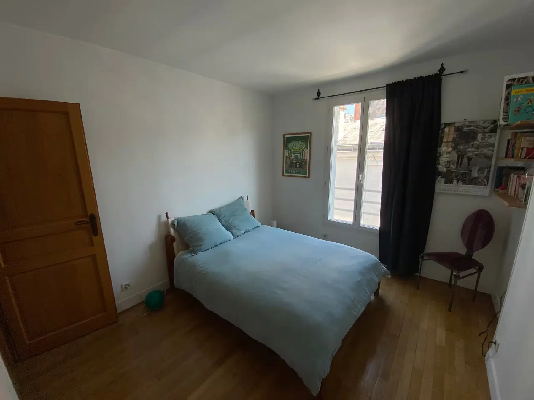 A bedroom with a bed beside a window with dark curtains.