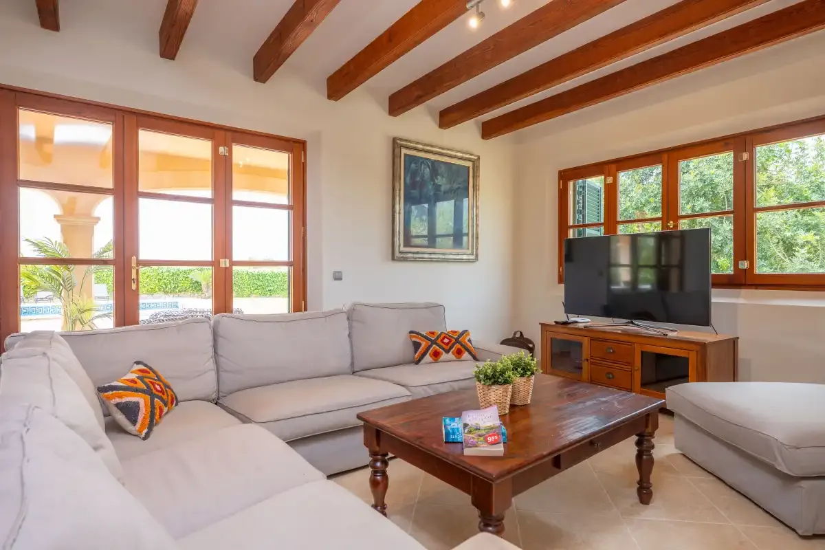 Una sala de estar luminosa con asientos, una mesa de centro y un televisor.