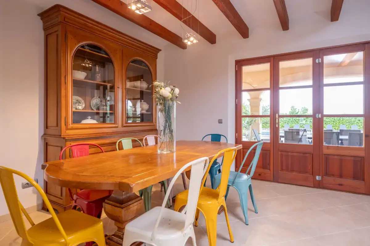 Un comedor con una mesa larga de madera y asientos de colores.