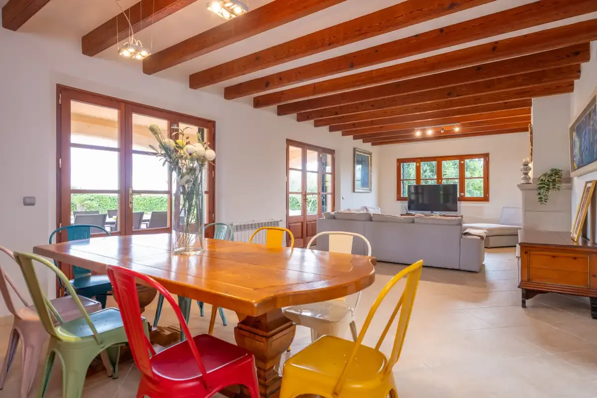 Un comedor y sala de estar con una mesa de madera y asientos bajo vigas vistas.