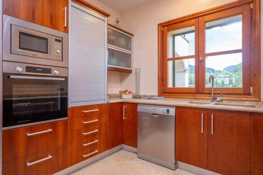 Una cocina con gabinetes de madera, electrodomésticos empotrados y una ventana sobre el fregadero.