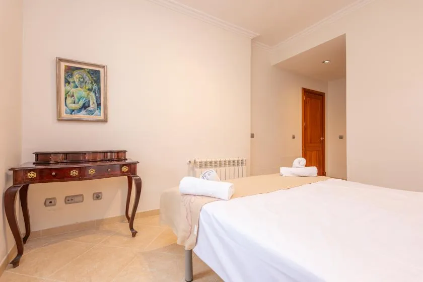 Un dormitorio con una cama bien tendida y una consola de madera.