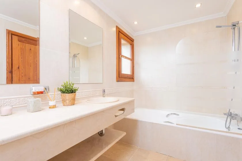 Un baño luminoso con un tocador largo, un espejo de pared y una bañera.