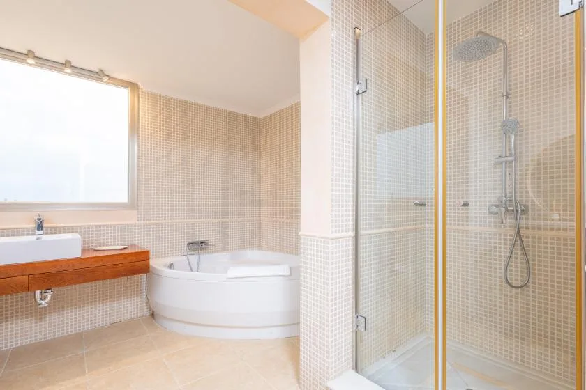 Un baño luminoso con bañera, lavabo y ducha con mampara de vidrio.