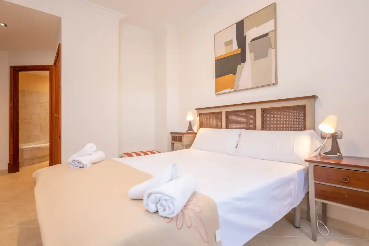 Un dormitorio con una cama bien hecha y toallas dobladas.