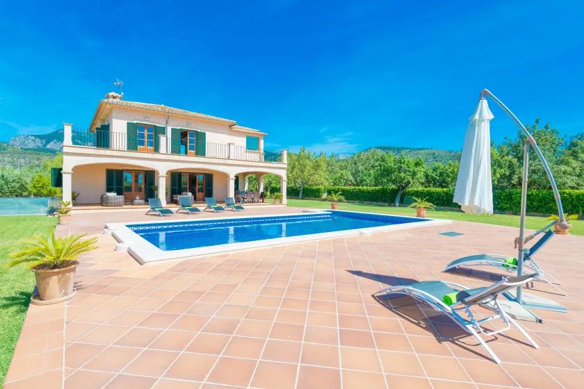 Una casa de dos plantas da a una piscina y un amplio patio embaldosado.