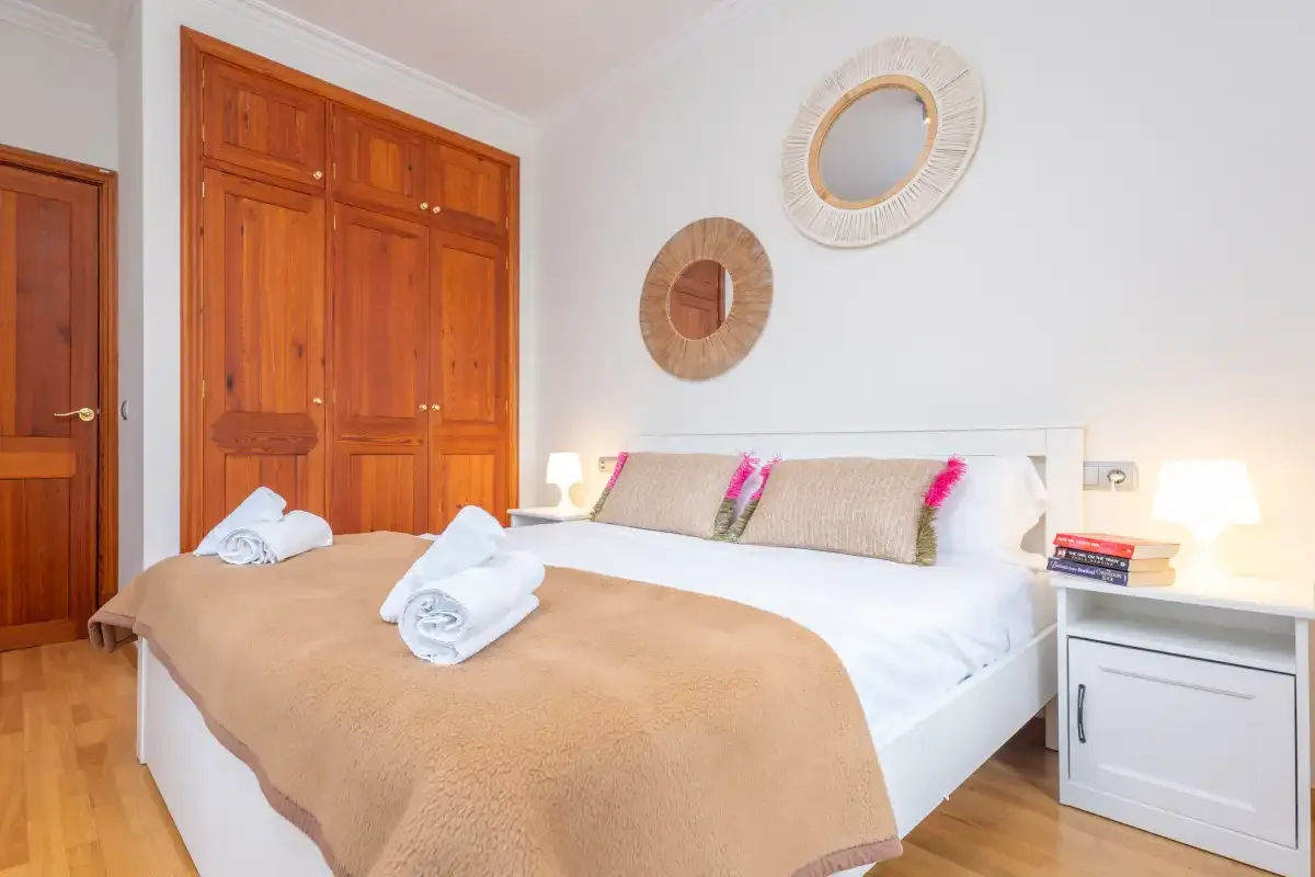 Un dormitorio con una cama grande, armarios de madera y espejos redondos en la pared.