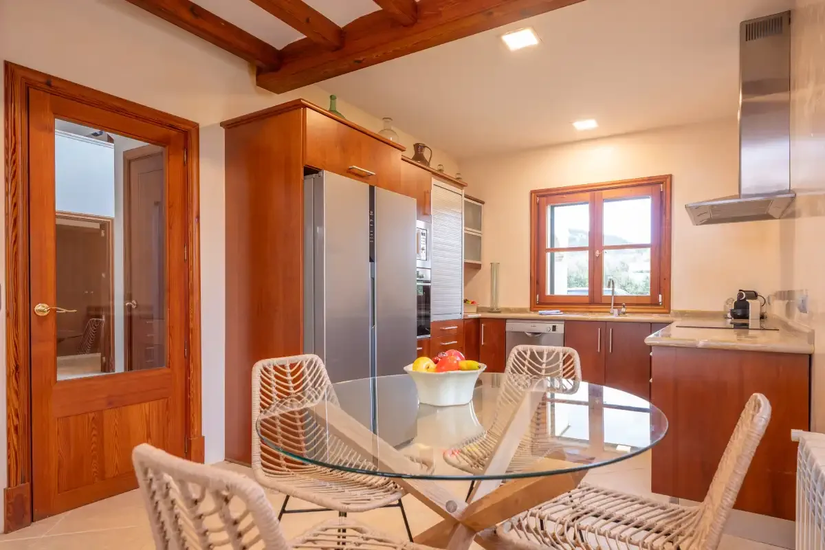 Una cocina con armarios de madera, electrodomésticos de acero inoxidable y una mesa de comedor de vidrio.