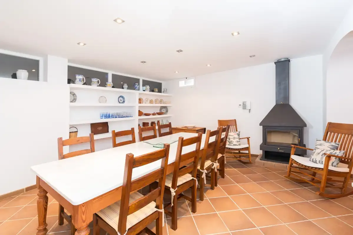 Un comedor con una larga mesa de madera y una chimenea.