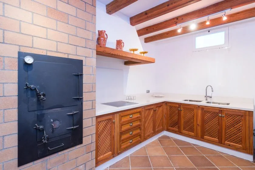 Una cocina con gabinetes de madera, un fregadero y vigas expuestas en el techo.