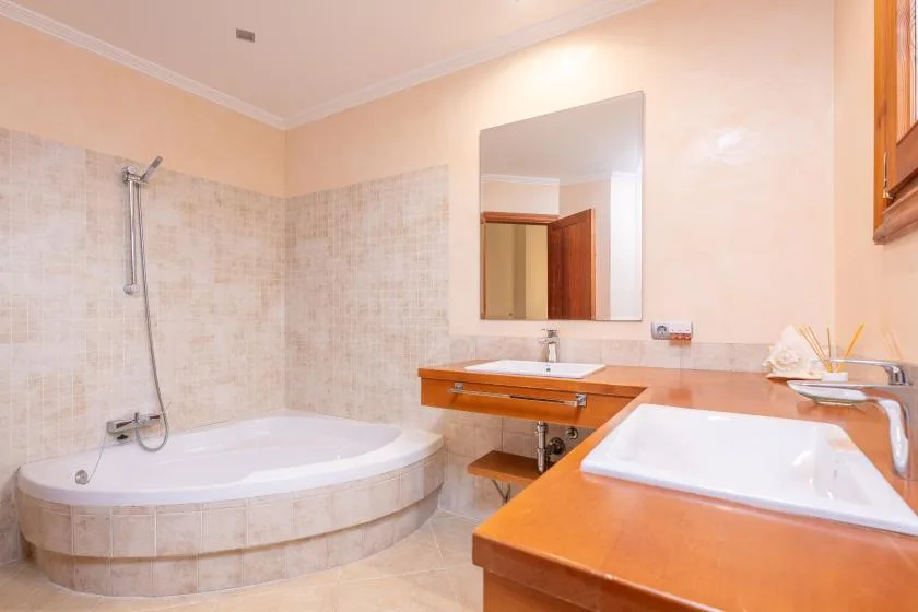 Un baño con bañera, ducha y dos tocadores de madera.