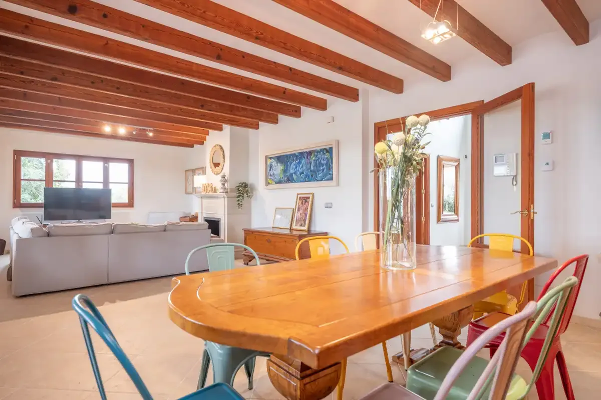 Un comedor con una gran mesa de madera se abre a una sala de estar.