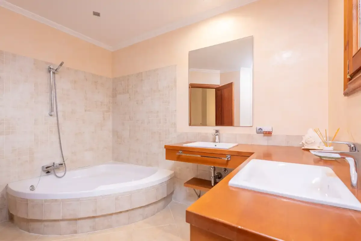 Un baño con bañera, lavabo y espejo de pared.