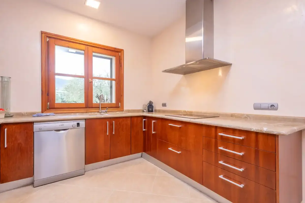Una cocina luminosa con armarios de madera, una encimera y una ventana.