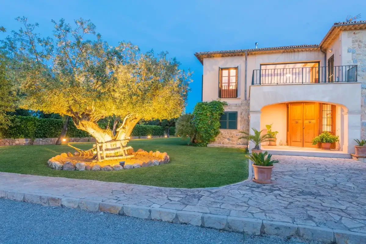 Una casa da a un patio de piedra junto a un césped y un árbol grande.