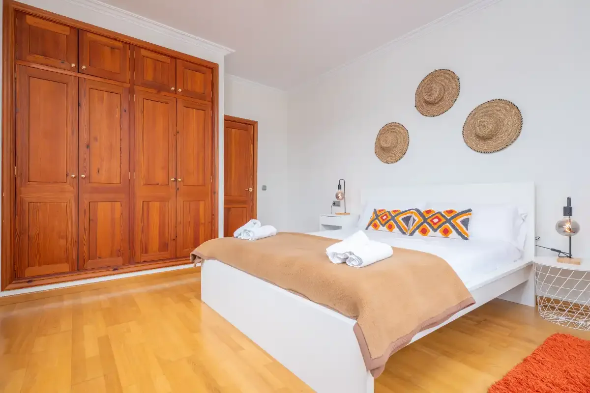 Un dormitorio con una cama doble, armarios de madera y adornos tejidos en la pared.
