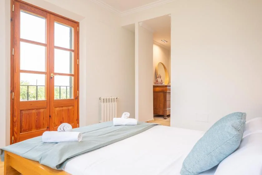 Un dormitorio con una cama junto a puertas altas de vidrio con marco de madera.