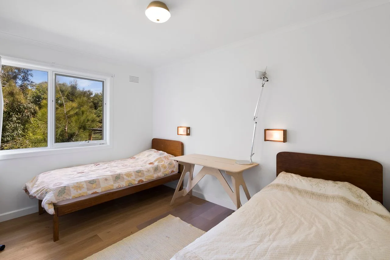 Un dormitorio con dos camas y una mesa pequeña entre ellas.