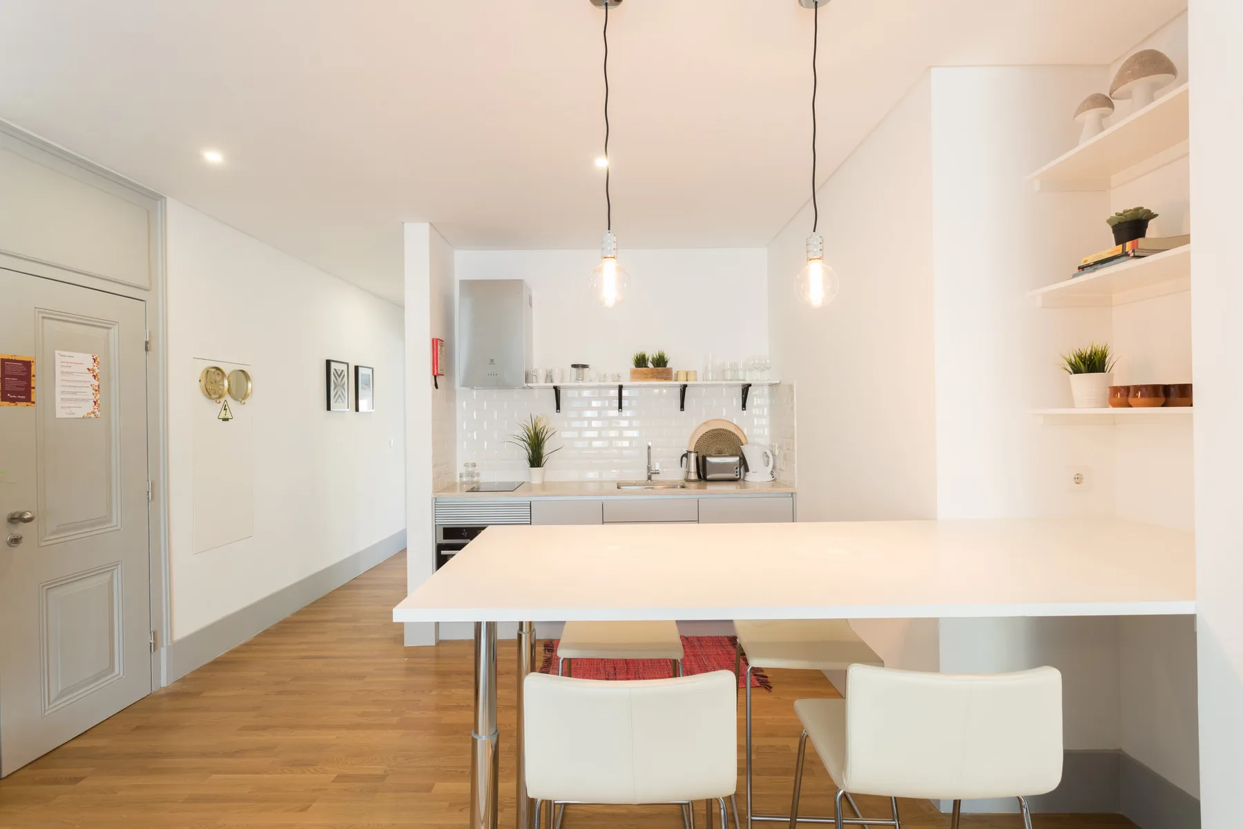 Una cocina y comedor luminosos con una barra larga y lámparas colgantes.